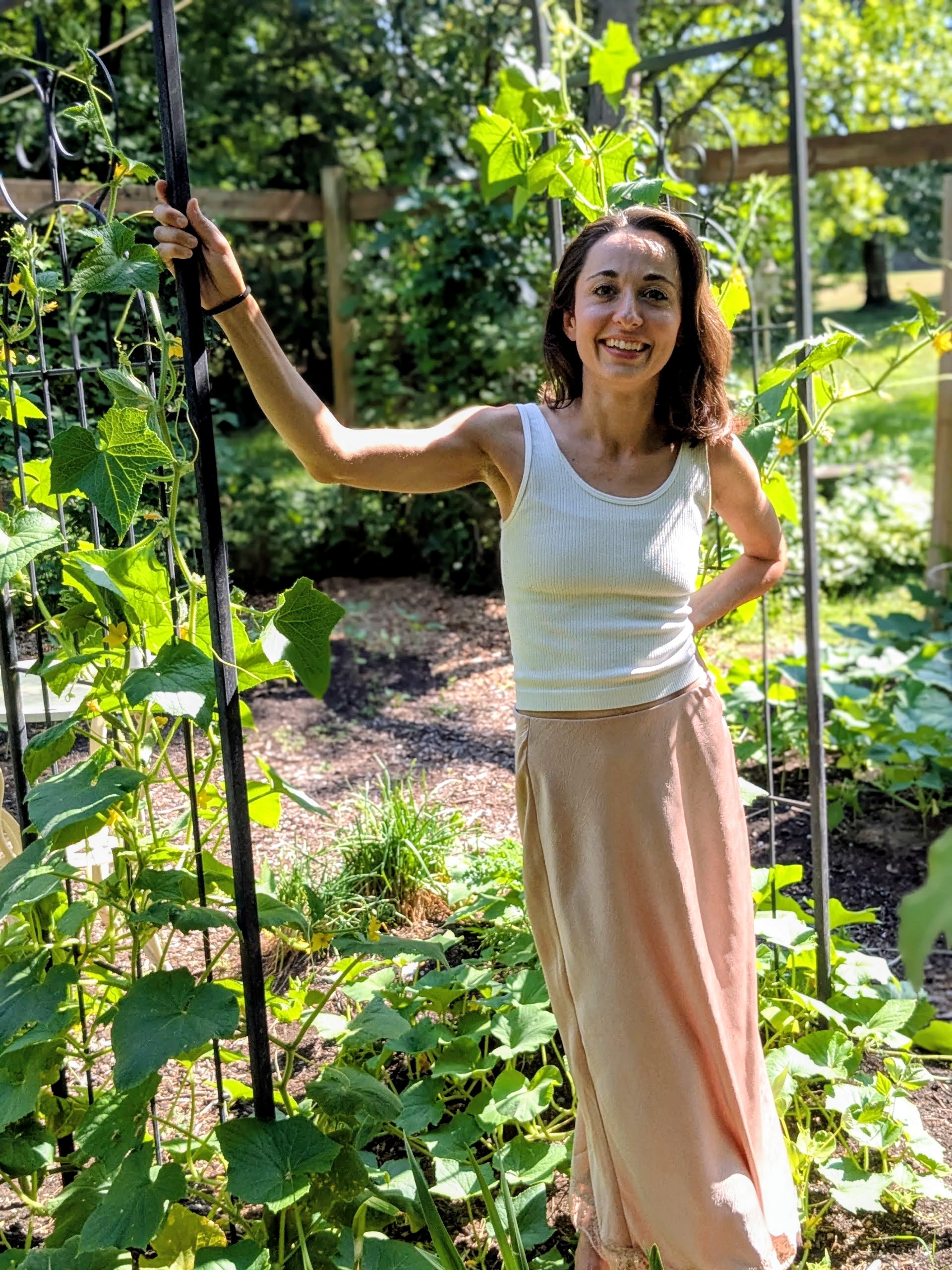 Sanja smiling among the plants in her garden.